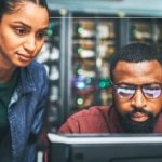 Two people look intently at a computer screen