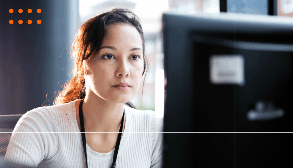 A woman looks at a computer screen, she is wearing a black lanyard