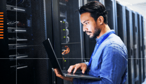 Man looking at computer near servers