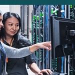 Workers point at a computer together