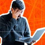 Man with hand to face in despair, holding a laptop.