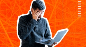 Man with hand to face in despair, holding a laptop.